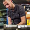 Technicien de Billis Climatisation en atelier, flexibles de raccordement au premier plan